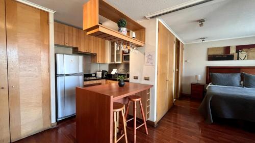 a small kitchen with a table and a refrigerator at Apartamentos City Centro Los Leones in Santiago