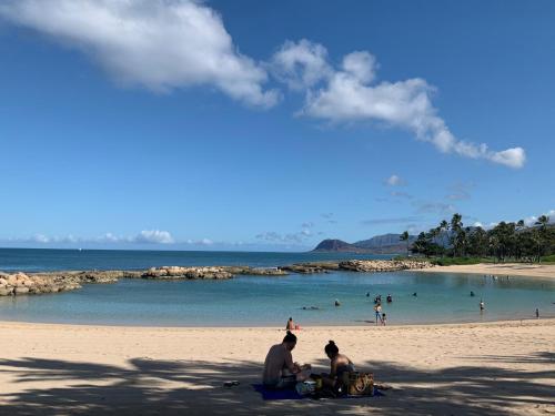 a group of people sitting on a beach at Ko Olina Ocean View Home Office in Kapolei