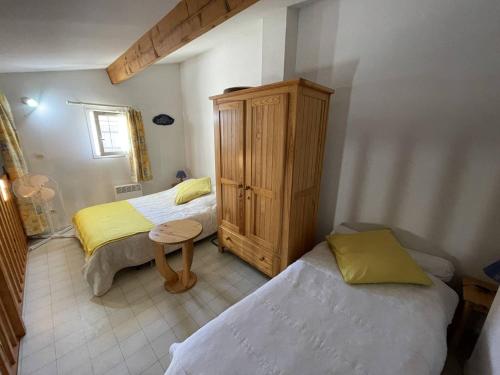 une chambre avec deux lits et une armoire en bois dans l'établissement Villa calme à Agde, proche plage, avec terrasse ombragée et parking privé - FR-1-723-101, au Cap d'Agde