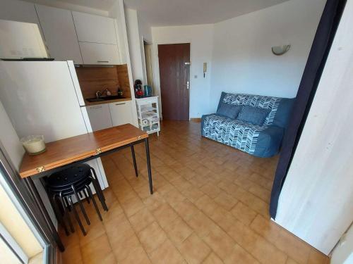 un salon avec une table et un canapé bleu dans l'établissement Appartement 2 pièces 4 pers avec terrasse, parking privé et accès direct plage à Marseillan - FR-1-326-791, à Marseillan