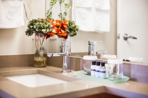 a bathroom counter with a sink with a vase of flowers at Executive Hotel Vancouver Airport in Richmond