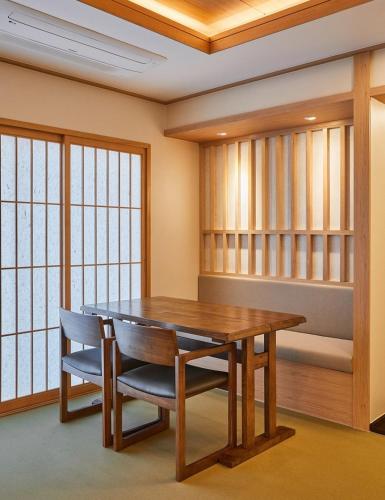 uma sala de jantar com uma mesa de madeira e cadeiras em Tomonoya Signature Ryokan Namhae em Namhae