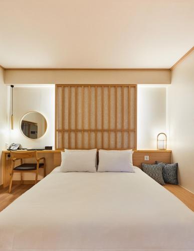 a bedroom with a large white bed and a desk at Tomonoya Signature Ryokan Namhae in Namhae