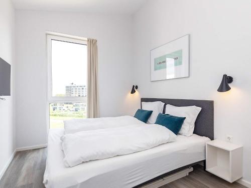 a white bedroom with a large bed with blue pillows at Apartment Wendtorf XXIX in Wendtorf