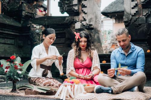 a group of three people sitting around a table with a cake at The Alus Cottage and Villa in Ubud