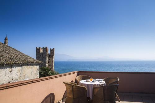 a table on a balcony with a view of the ocean at Hotel Degli Oleandri in Sirmione