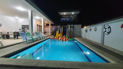 a large swimming pool with chairs and a playground at Family POOL VILLA CHAAM in Cha Am