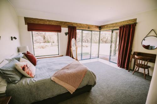 sypialnia z łóżkiem i dużym oknem w obiekcie The River House Wanaka w mieście Wanaka