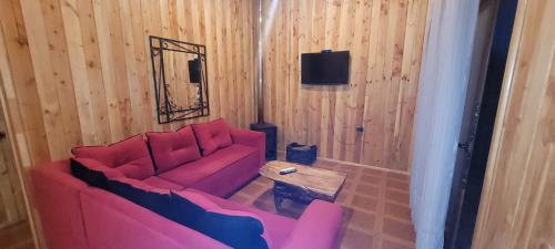 a living room with a pink couch and a table at Cabañas Troncos de Relin in Panguipulli