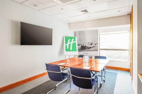 a conference room with a wooden table and blue chairs at Holiday Inn Rochester-Chatham by IHG in Chatham