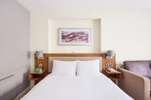 a bedroom with a bed and a chair at Holiday Inn Rochester-Chatham by IHG in Chatham