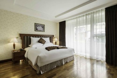a bedroom with a large bed and a large window at Rex Hotel in Ho Chi Minh City