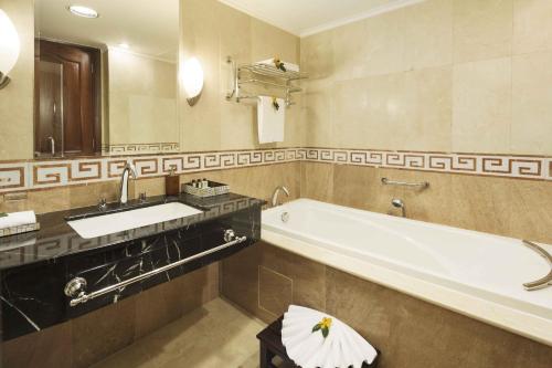 a bathroom with a tub and a sink and a mirror at Rex Hotel in Ho Chi Minh City