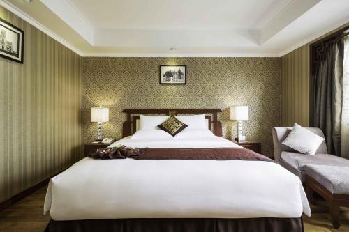 a hotel room with a large bed and a chair at Rex Hotel in Ho Chi Minh City