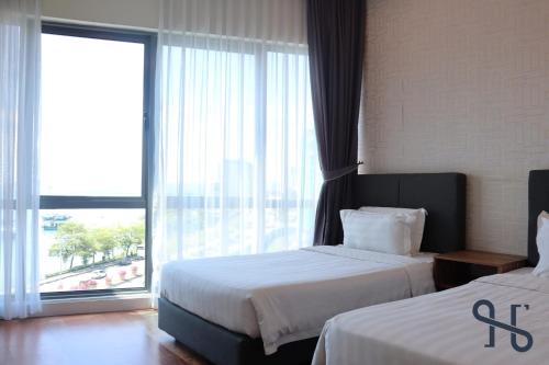 a hotel room with two beds and a large window at Homesuite' Home at The Loft in Kota Kinabalu