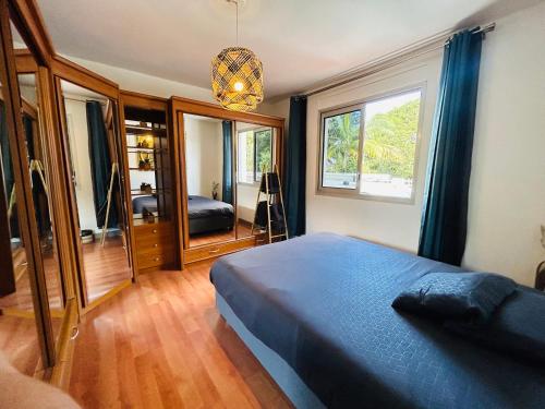 ein Schlafzimmer mit einem blauen Bett und einem großen Fenster in der Unterkunft MEGA APPARTEMENT in Le Tampon