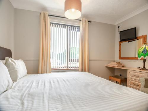 a bedroom with a large white bed and a window at Clover Cottage - W40835 in Horsford
