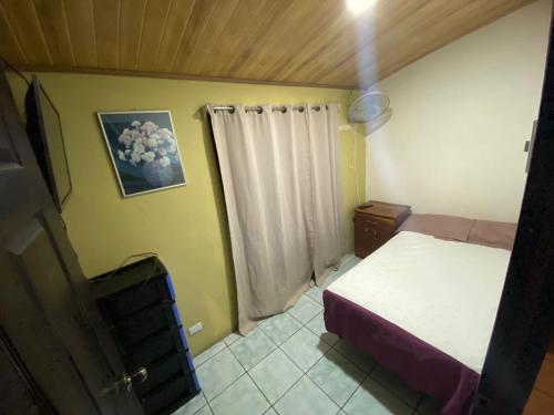 Habitación pequeña con cama y ventana en La Casa de Cachi en Paquera