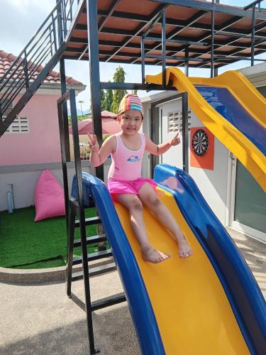 a little girl sitting on a slide at a playground at Family POOL VILLA CHAAM in Cha Am
