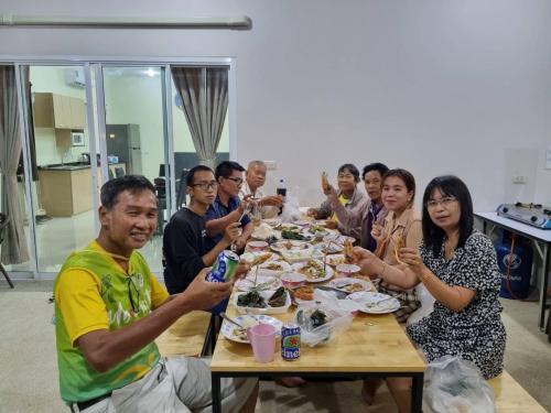 a group of people sitting around a table eating food at Family POOL VILLA CHAAM in Cha Am