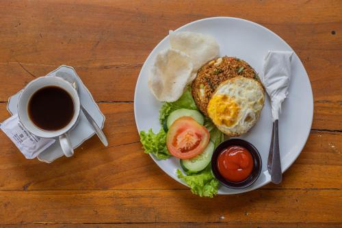 a plate of food with a sandwich and a cup of coffee at Favorit Exclusive Villa & Bungalow in Nusa Penida