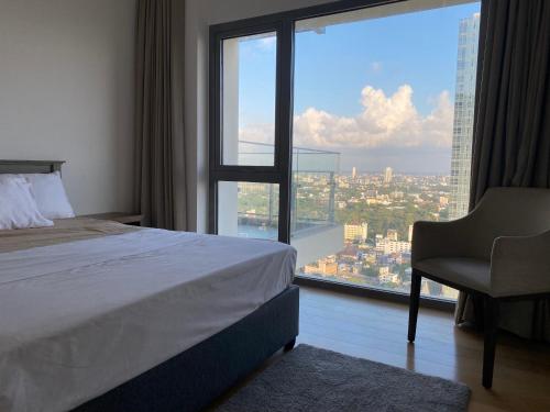 a bedroom with a bed and a chair and a large window at Altair Colombo - View, Location, Ultra Luxury! in Colombo