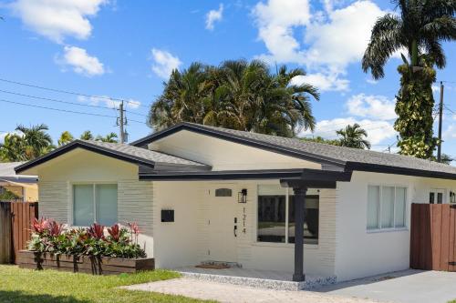 a white house with a fence and palm trees at Newly Remodeled House in Miami - 3BR House with Private Yard - 5 Min ride to Hollywood Beach in Hollywood
