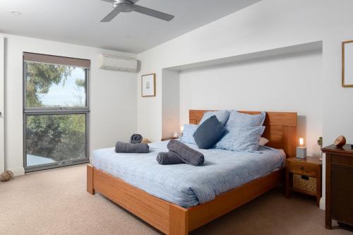 een slaapkamer met een bed met blauwe kussens en een raam bij Smithys Shore Thing in Smiths Beach