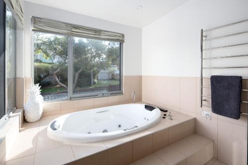een groot wit bad in een badkamer met een raam bij Smithys Shore Thing in Smiths Beach