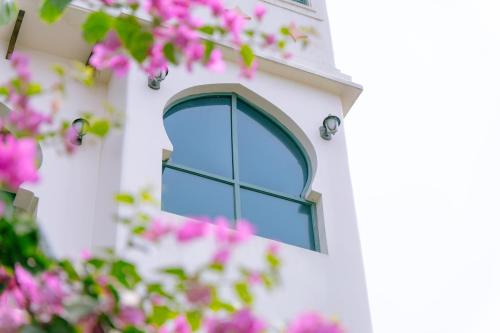 a window on the side of a building with pink flowers at Alsahar Hoi An Boutique Villa in Hoi An