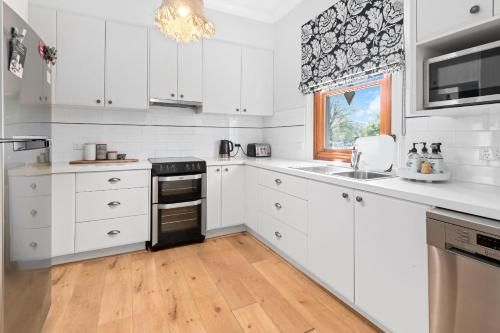a kitchen with white cabinets and a black stove top oven at Belle Cottage on March - Central High-End Heritage in Orange