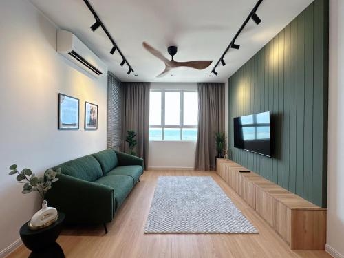 a living room with a green couch and a television at TUJU Homes (SeaView, Drawbridge & KTCC Mall) in Kuala Terengganu