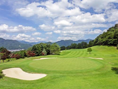 a green golf course with a tree on a hill at Crest Asago in Asago