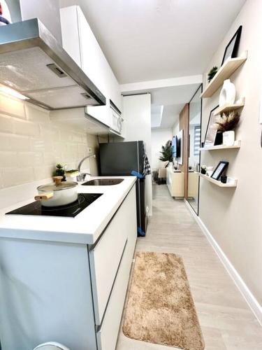 uma cozinha branca com um lavatório e um fogão em Aurum Latte Suite at Azure North em Lagundi