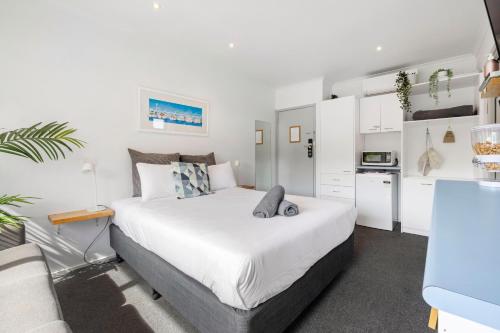 a bedroom with a large white bed and a kitchen at Moody's Motel in Blairgowrie