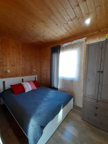 a bedroom with a blue bed with a window at Przyjazne domki in Lubogoszcz