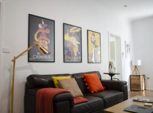 una sala de estar con un sofá de cuero negro y carteles en Mary Lemon Cottage - Heritage Home en Orange