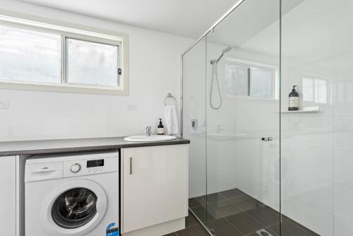 a white bathroom with a washing machine and a shower at The Leaning Oak Holiday Lifestyles - Lake Conjola in Conjola