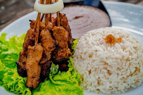 a plate of food with rice and chicken and lettuce at Umadhatu Resort by Amerta in Tabanan