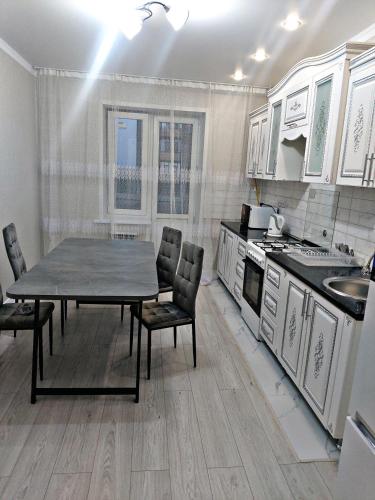 eine Küche mit einem Tisch und Stühlen in der Unterkunft Абая 244 in Oral