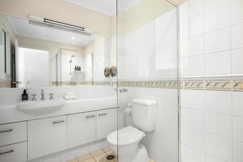Un baño blanco con inodoro y lavabo. en Villa Aqua Riverside Retreat with Pool, en Noosaville