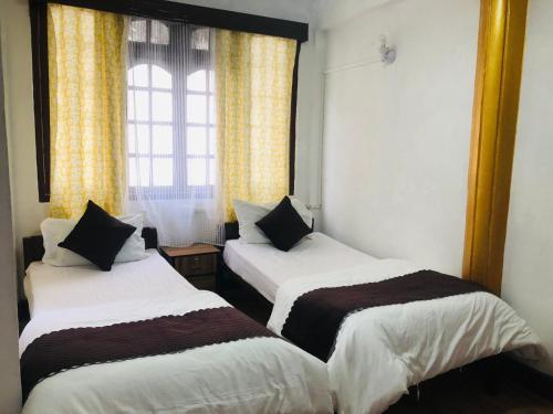 dwa łóżka w pokoju z oknem w obiekcie Darjeeling Homestay w mieście Dardżyling