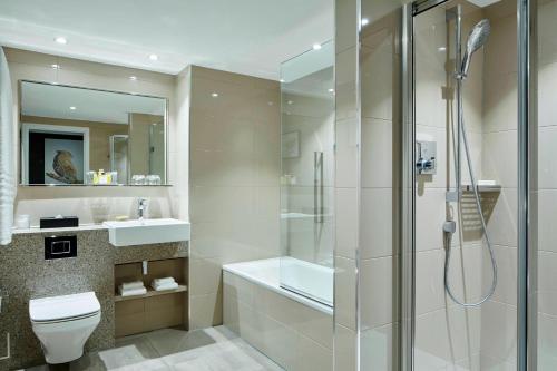 a bathroom with a shower and a toilet and a sink at London Heathrow Marriott Hotel in Hillingdon