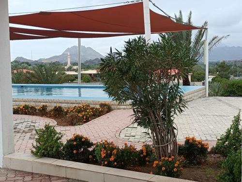 a large red umbrella next to a swimming pool at Peace Farm in Hatta