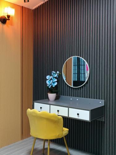 a yellow chair and a dresser and a mirror at De sepakat cottage private pool in Kuantan
