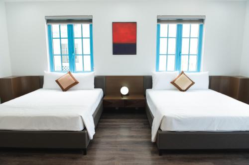 two beds in a room with two windows at Luxury Homestay Sun Feria Ha Long in Ha Long