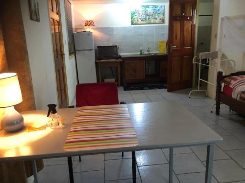 a kitchen with a table with a lamp on it at Unu Pikin Guesthouse in Paramaribo