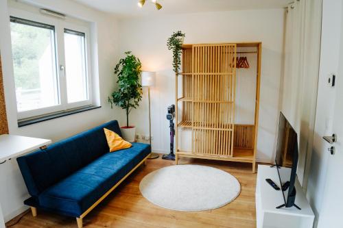 a living room with a blue couch and a tv at Design Home Office & Central Hideaway - EAH, ZEISS, SCHOTT in 5 min in Jena