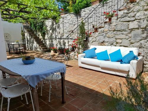a patio with a white couch and a table with blue pillows at Casa Sole di Toscana con 5 camere, grande terrazza panoramica, giardino e vasca relax idromassaggio in Monterotondo