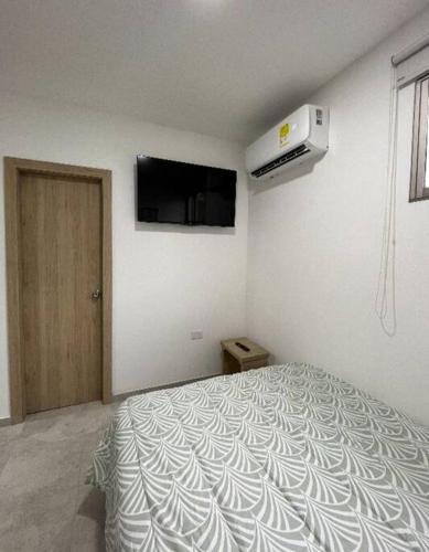 a white bedroom with a bed and a tv on the wall at Acogedor aparta/estudio al norte cc viva in Barranquilla